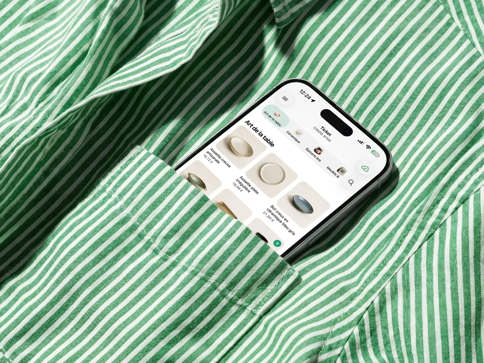 Un smartphone glissé dans la poche d'une chemise rayée verte, affichant la caisse Gillia avec des articles d'art de la table