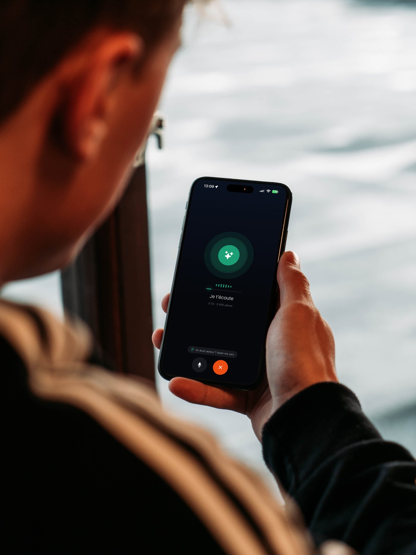 A person holding a smartphone showing Gillia's voice screen, “I'm listening”