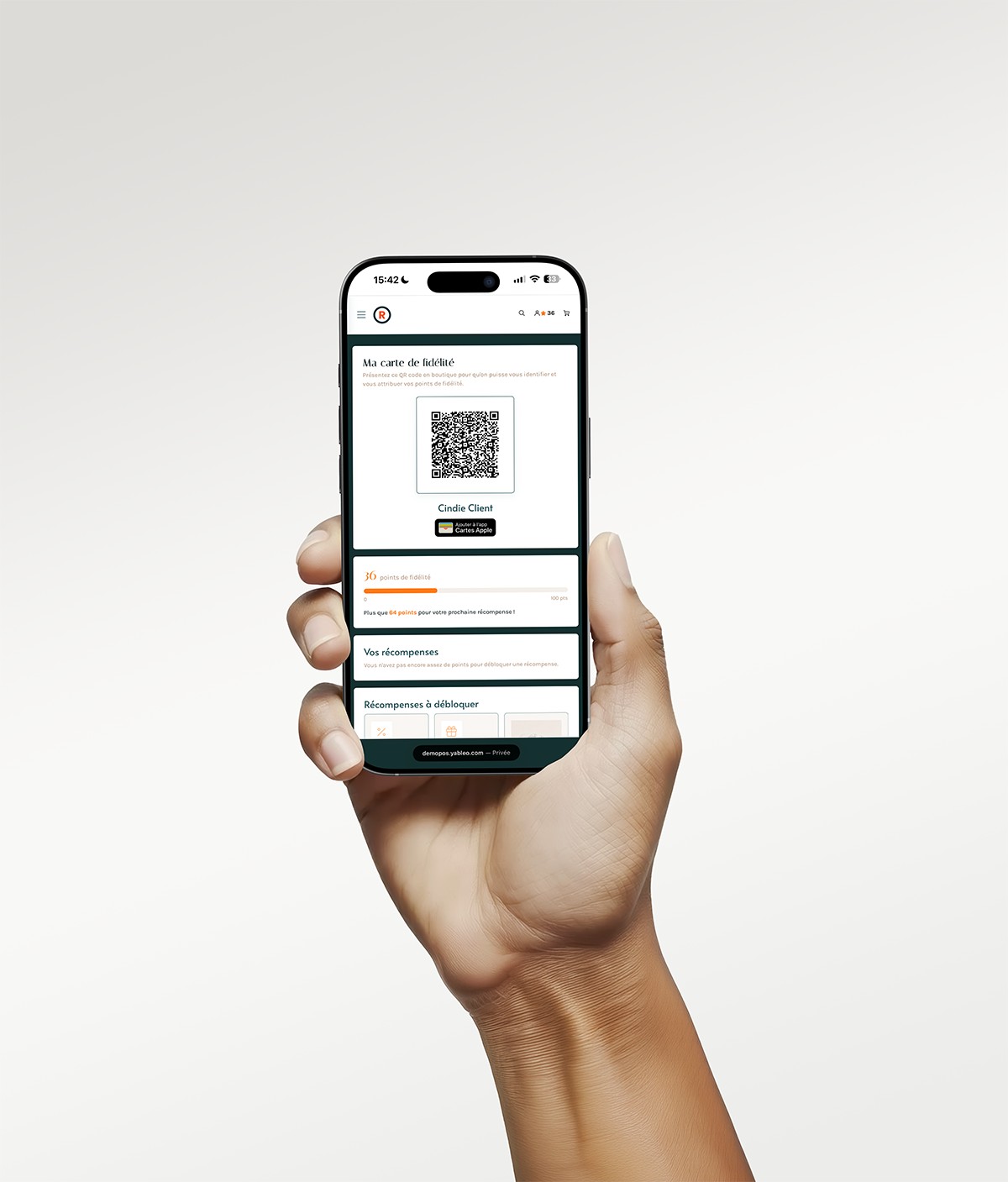 A hand holding a smartphone showing the loyalty card: QR code to present in store, 36 points out of 100 and rewards to unlock