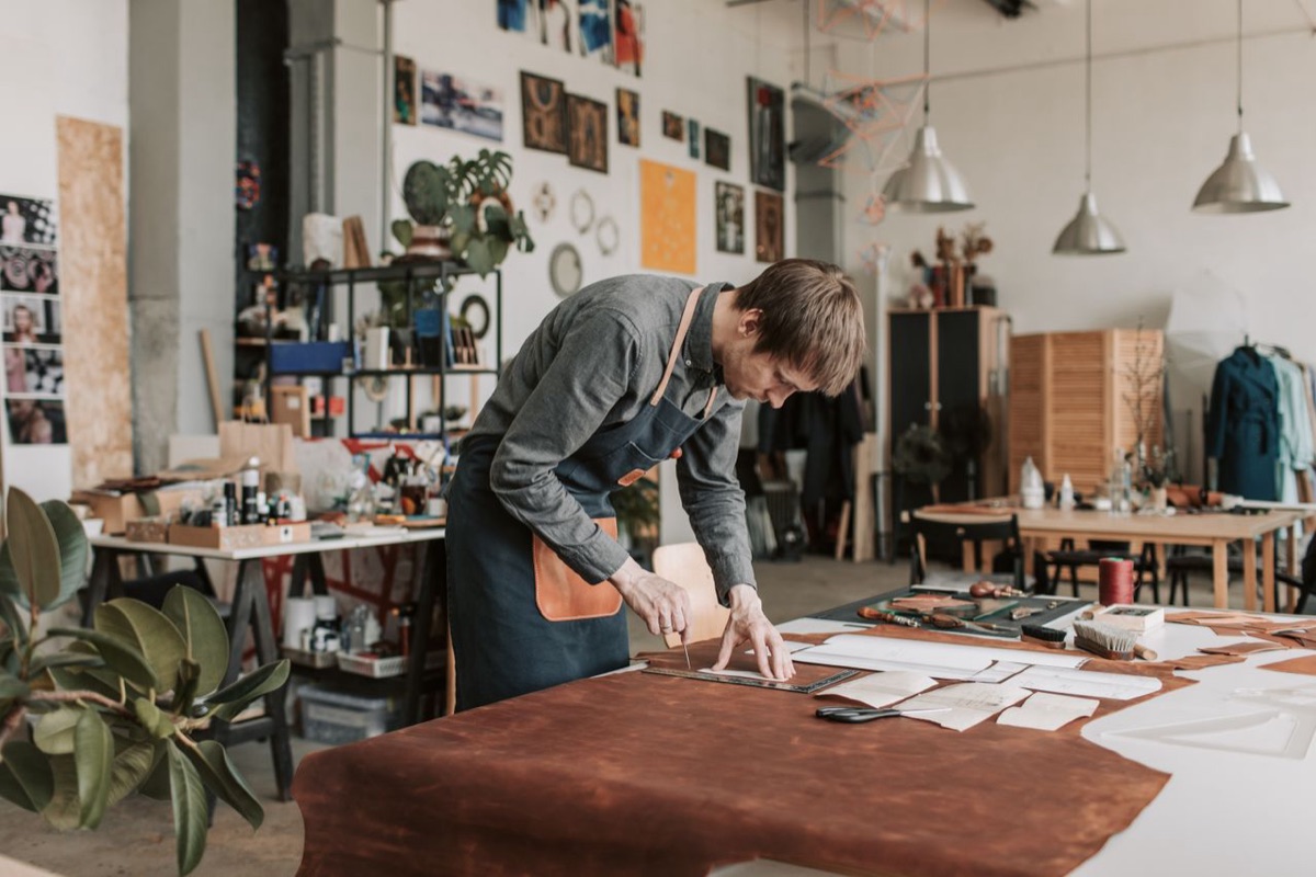 Un artesano corta cuero sobre la mesa de su taller
