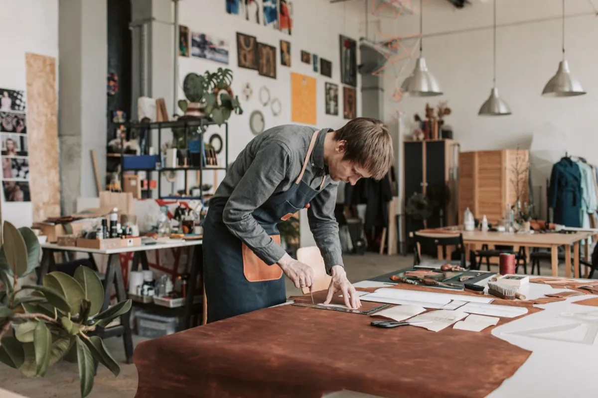 Un artisan découpe du cuir sur la table de son atelier